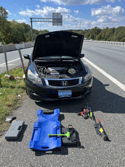 Honda with its hood open and tools arranged alongside the highway